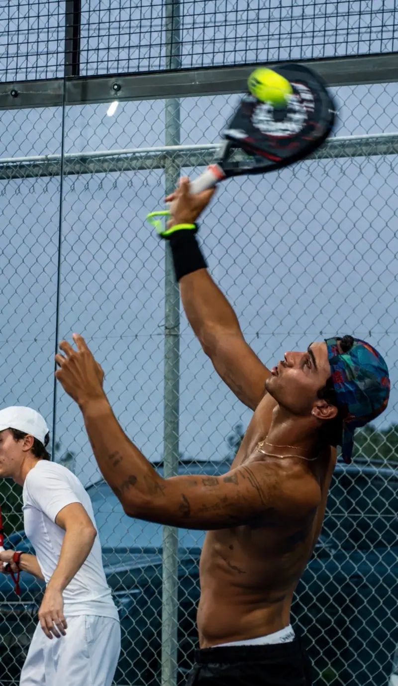 Padel player mid-serve on court