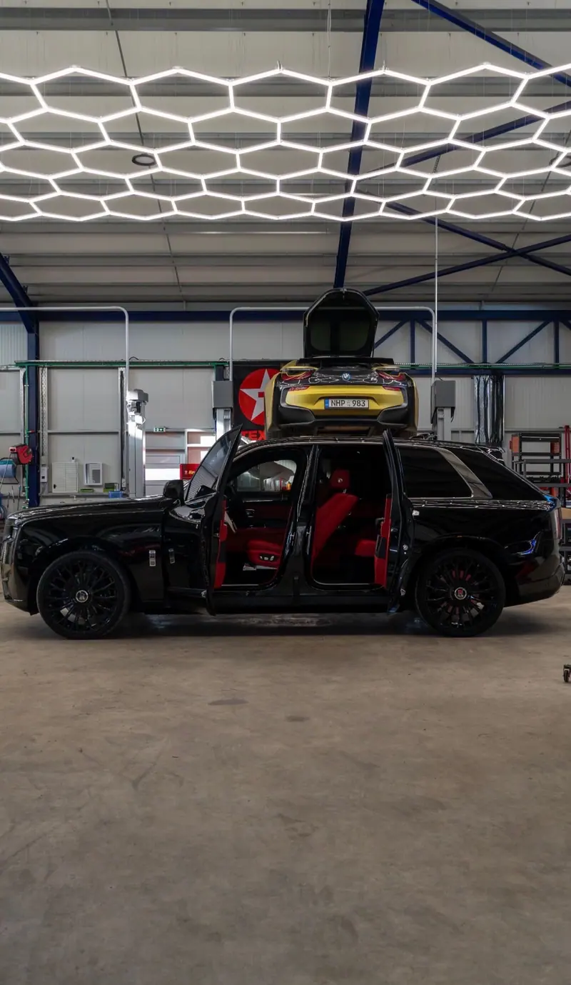 Black SUV with its doors open under hexagon lighting inside the workshop