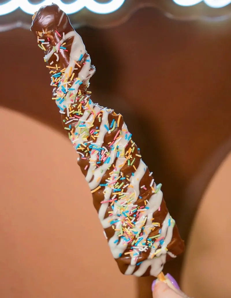 Chocolate-dipped Sweetory treat with white chocolate drizzle and sprinkles